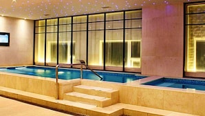 An indoor swimming pool with steps leading into the water, surrounded by large windows and a ceiling with star-like lights. - Ruixin Hotel (Fuzhou)