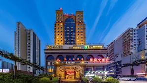 A multi-story hotel with a prominent central tower, multiple balconies, and a well-lit entrance. - Ruixin Hotel (Fuzhou)
