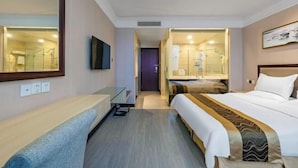 A hotel room with a large bed, a bedside table, a mirror, and a television. - Ruixin Hotel (Fuqing)