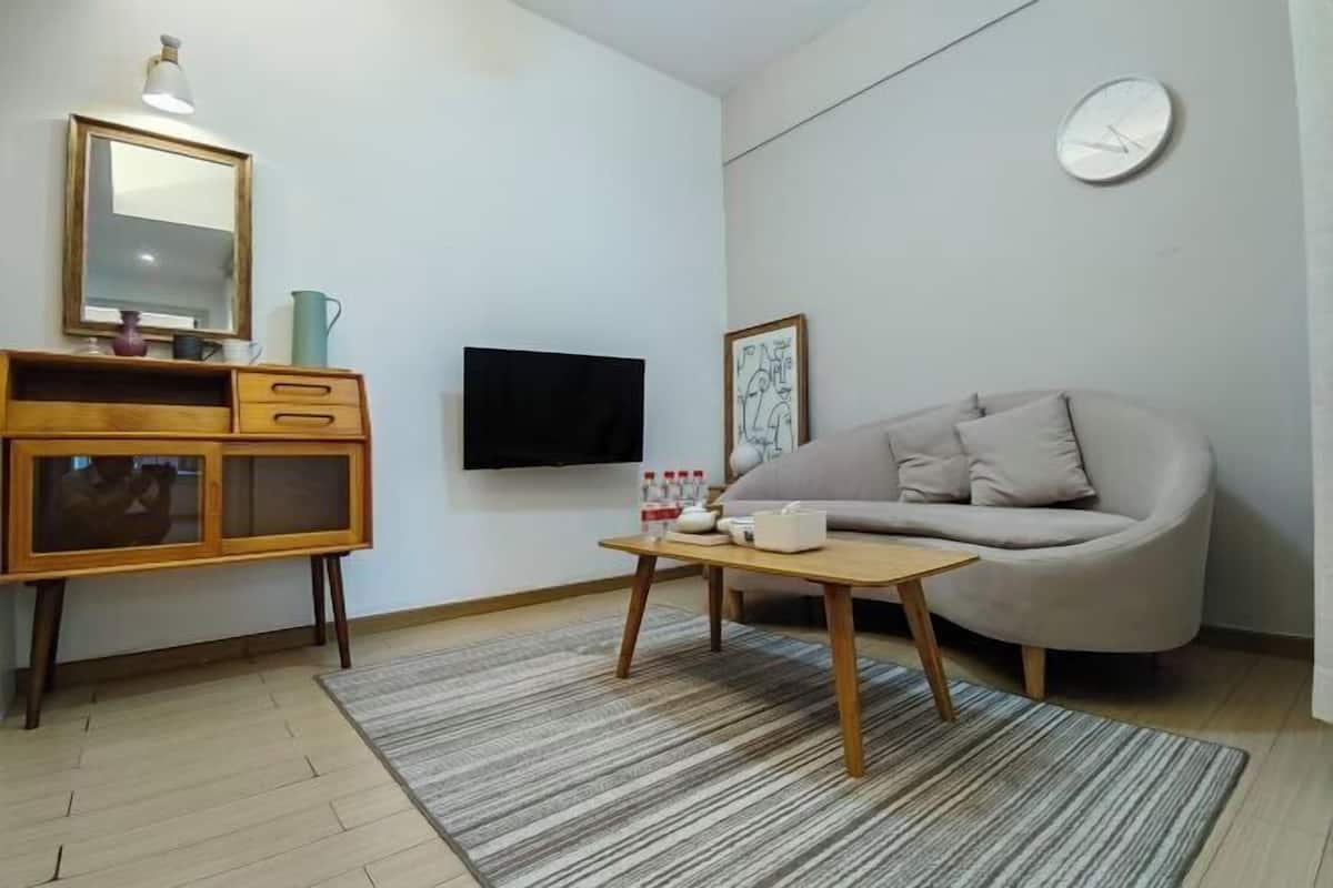 A living room with a sofa, a coffee table, a TV, a wooden cabinet, and a rug.