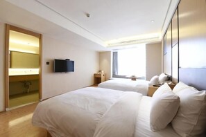 Ein Hotelzimmer mit zwei Betten, einem Fernseher, einem Spiegel und einem Fenster mit Vorhängen.