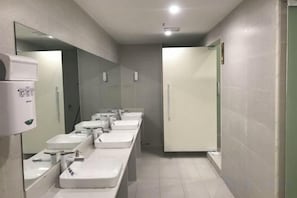 A restroom with multiple sinks, a hand sanitizer dispenser, and a mirror. - Lilong hotel (Huizhou)