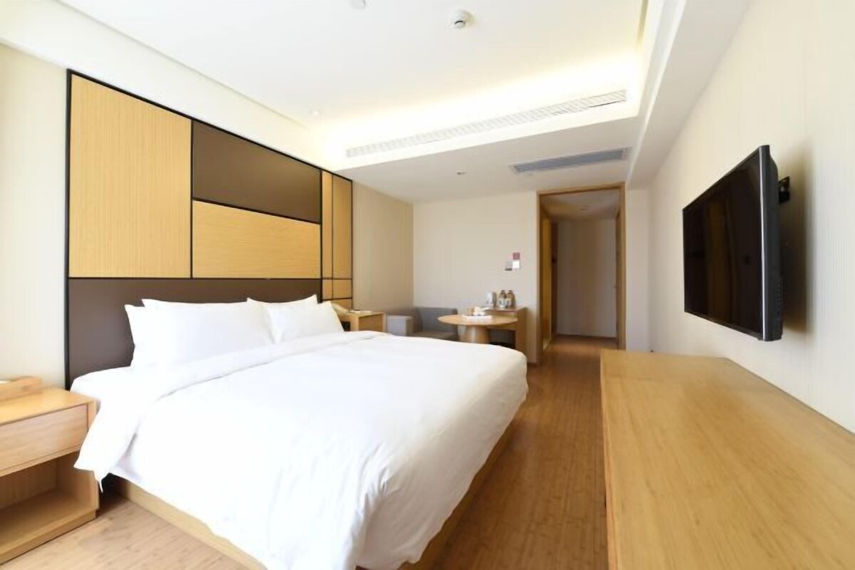 Ein Hotelzimmer mit Bett, Nachttisch, Fernseher und einem kleinen Tisch mit Lampe.