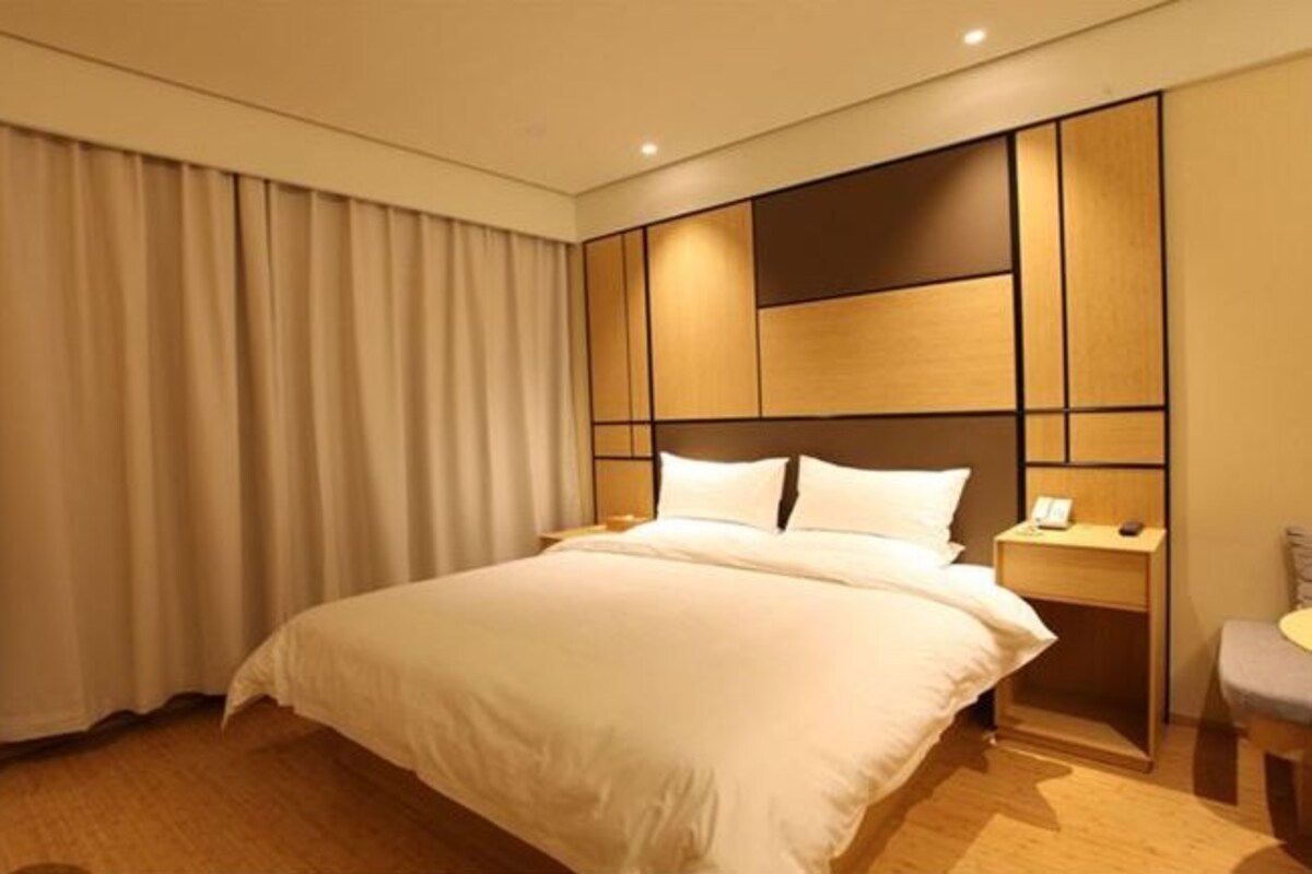 A hotel room with a large bed, a nightstand, and a chair.