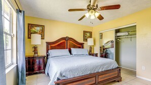 A bedroom with a wooden bed, two bedside tables, a ceiling fan, and a large mirror. - Mins to the Coast: Port St Lucie Home w/ Lanai! (Fort Pierce)