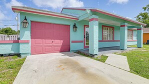 A two-story house with a red garage door, teal exterior, and a small front porch. - Mins to the Coast: Port St Lucie Home w/ Lanai! (Fort Pierce)