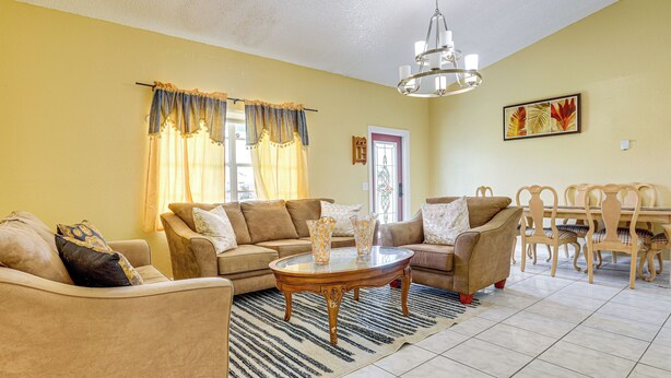 A living room with a sofa set, a dining table with chairs, and a chandelier. - Mins to the Coast: Port St Lucie Home w/ Lanai! (Fort Pierce)