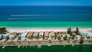 Vista aérea de uma área costeira com praia, marina e edifícios à beira-mar.