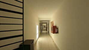 A hallway with a staircase on the left, a fire extinguisher on the right, and a door at the end. - Bed and Brew (Chennai)