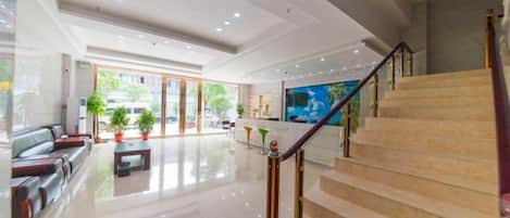 A hotel lobby with a staircase, seating area, and a large painting.