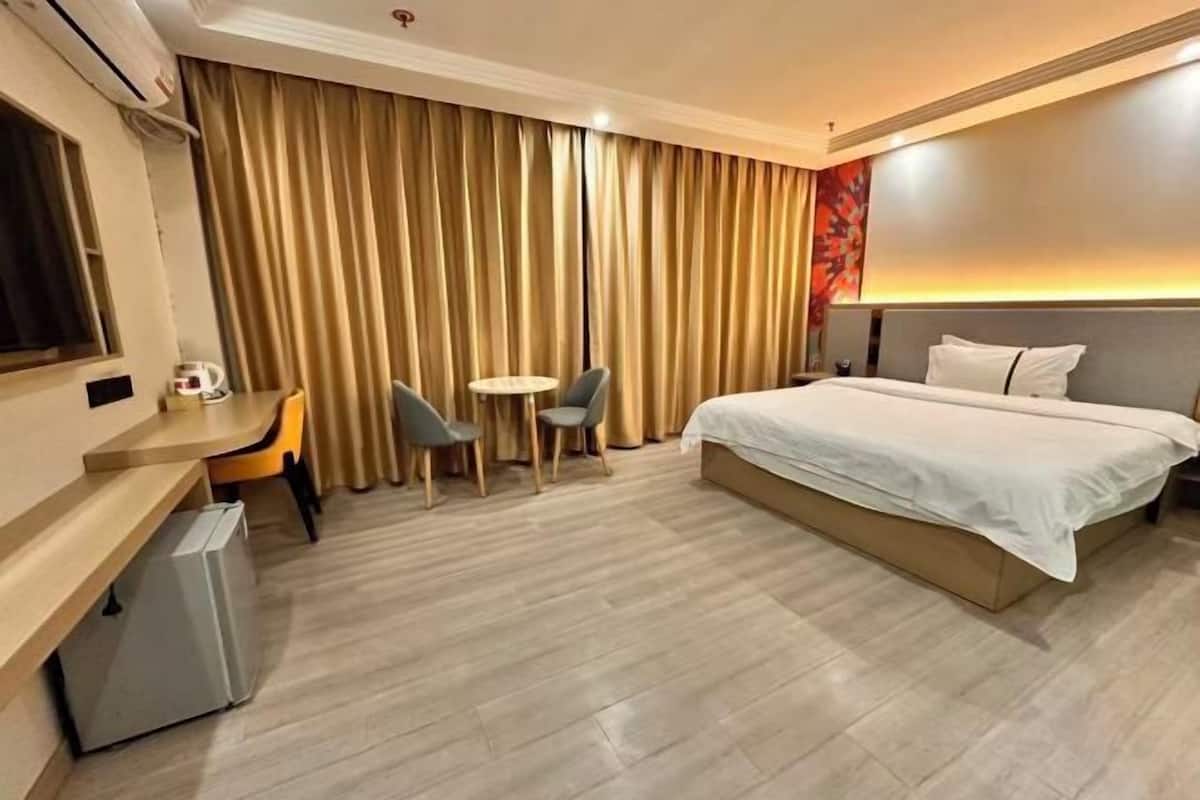 A hotel room with a bed, desk, chairs, and a small table.