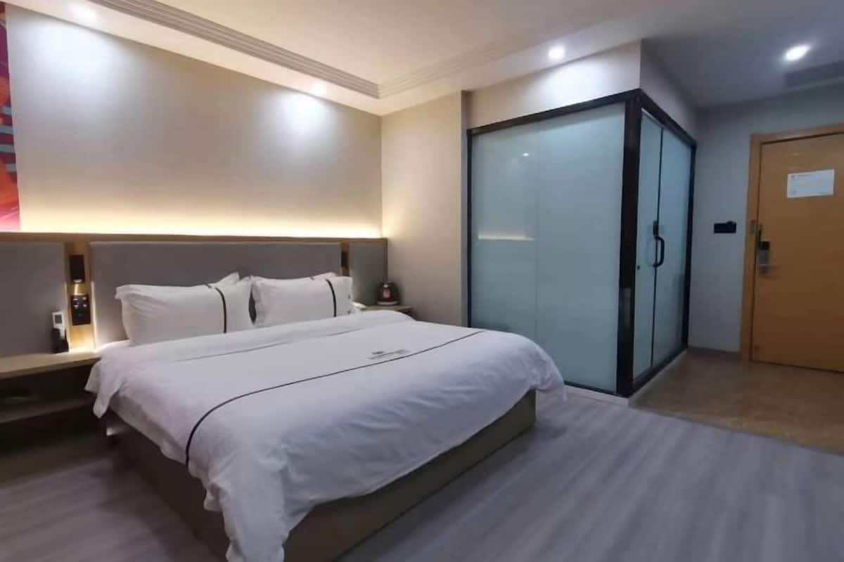 A hotel room with a bed, bedside tables, a wardrobe, and a door.