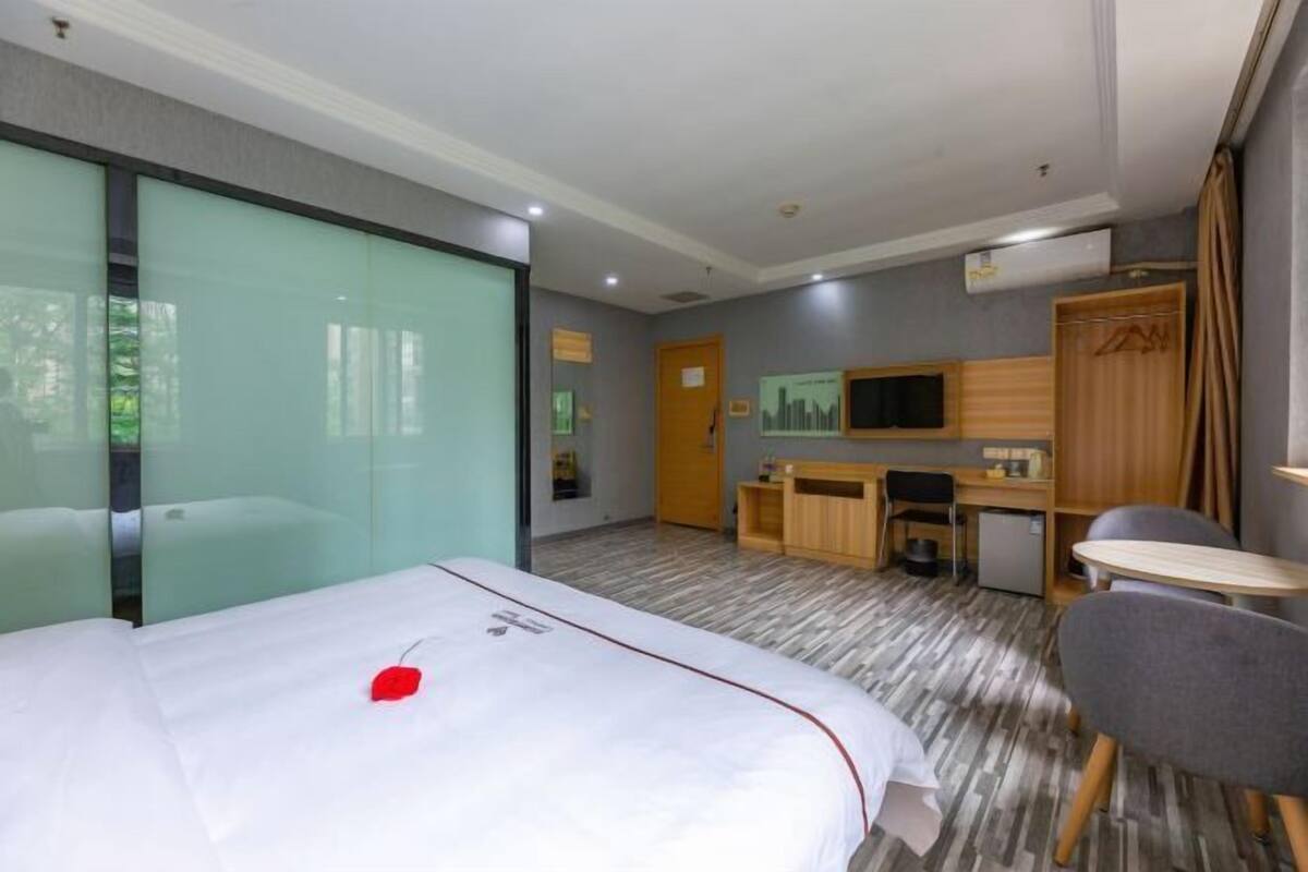 A hotel room with a bed, a desk, a chair, a television, and a wardrobe.