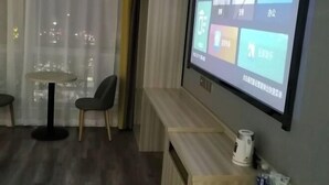 A hotel room with a large screen displaying a user interface, a sofa, a small table, and a cabinet. - Century Business Hotel (Zuoling New Town) (Wuhan)