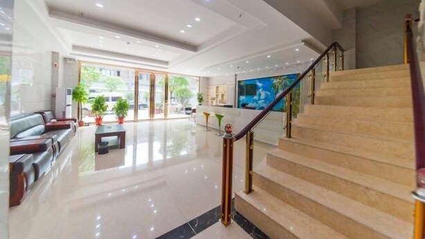 A hotel lobby with a staircase, seating area, and a large TV screen. - Century Business Hotel (Zuoling New Town) (Wuhan)