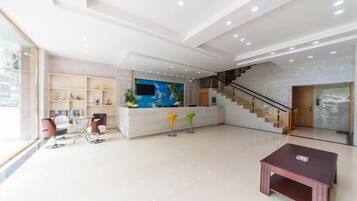 A spacious lobby with a reception desk, seating area, and a staircase.