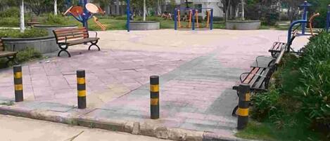 A paved pedestrian area with benches, bollards, and exercise equipment.
