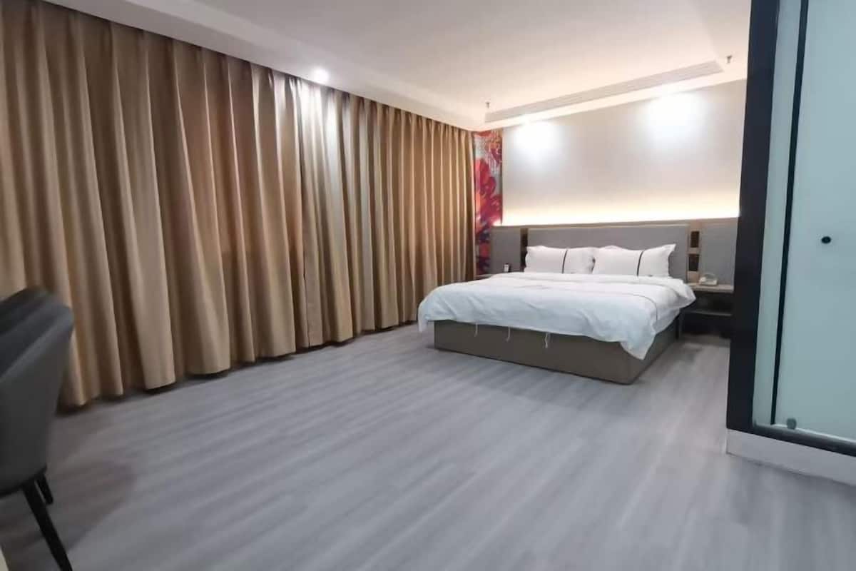 A modern hotel room with a large bed, a desk, and a chair.