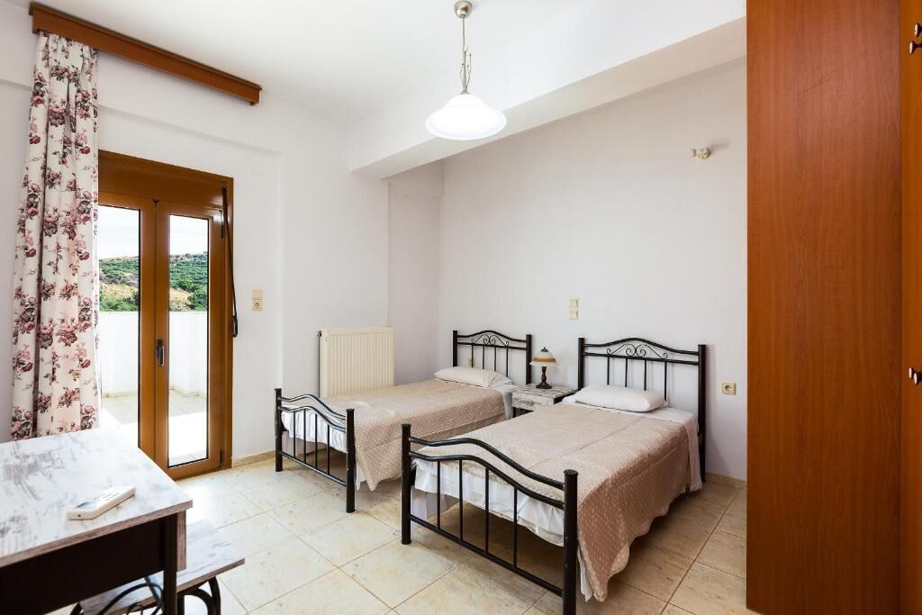 Ein Schlafzimmer mit zwei Einzelbetten, einer Holztür, einem Heizkörper und einem Tisch mit einem Stuhl.