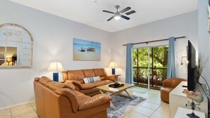 Ein Wohnzimmer mit einer Couch, einem Couchtisch, einem Fernseher und einem Deckenventilator.