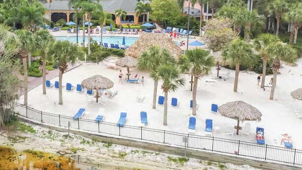 Ein Resort mit Poolbereich, Liegestühlen, Palmen und einem kleinen Gebäude.
