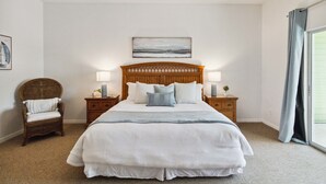 A bedroom with a large bed, two nightstands, a wicker chair, a ceiling fan, a painting, and a view through a window. - BB 1016 Huge Updated 3BR unit Marvel room sleeps 8 (Davenport)