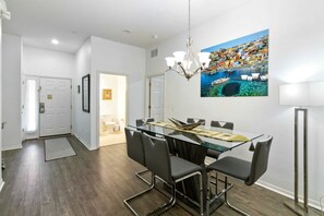 Un coin repas avec une table en verre, des chaises noires et un lustre.