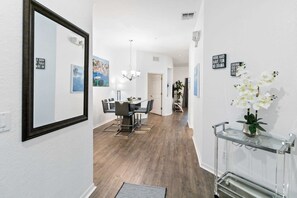 Un couloir comprenant un coin repas, un miroir et une console sur laquelle est posé un vase.