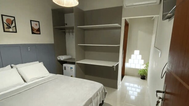 A modern bedroom with a large bed, a hanging light fixture, and a small bedside table. - Pousada Brunetti (Penha)