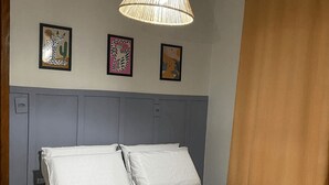 A bedroom with a bed, a hanging light fixture, and three framed pictures on the wall. - Pousada Brunetti (Penha)