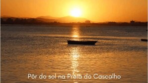 A sunset view from a hotel in Penha, featuring a calm body of water and a boat. - Pousada Brunetti (Penha)