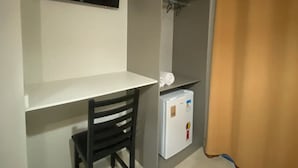 A small room with a desk, chair, and a white refrigerator. - Pousada Brunetti (Penha)