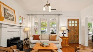 A cozy living room with a fireplace, two sofas, a coffee table, and a wooden door. - Luxury Paso Bungalow • Hot Tub & EV Charger (Paso Robles)