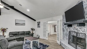 Un salon moderne avec une cheminée en pierre, un téléviseur à écran plat et un ensemble de canapés.