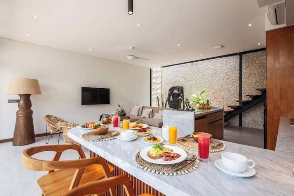 Ein Frühstücksarrangement mit einem Marmortisch, Korbstühlen und einer Wand aus Stein im Hintergrund.