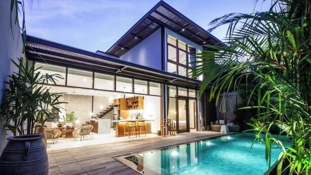 A modern house with a swimming pool, a wooden deck, and a kitchen area.