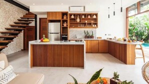 A modern kitchen with a central island, wooden cabinetry, and a stone accent wall.