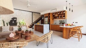 A modern kitchen with wooden cabinets, a central island, and a dining area with wicker chairs.