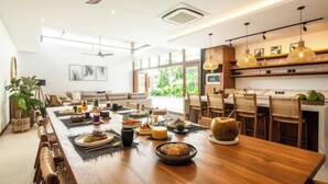 A modern dining area with a wooden table set for a meal, surrounded by chairs. - Big pool 5 BR Villa Canggu Prime location, 5 min to Berawa beach, . (Tibubeneng)