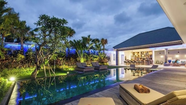A poolside area with lounge chairs and a well-lit indoor space.