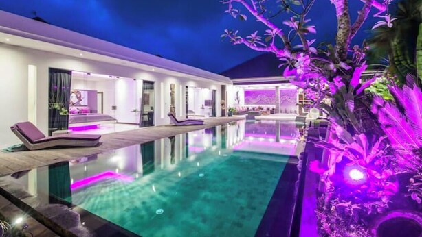 A modern infinity pool with a clear view of the sky, surrounded by a well-lit outdoor area with lounge chairs. - Cozy 4 BR Modern Villa in Seminyak, Large Pool, Perfect and Fantastic (Kerobokan Kelod, Kec. Kuta Utara)