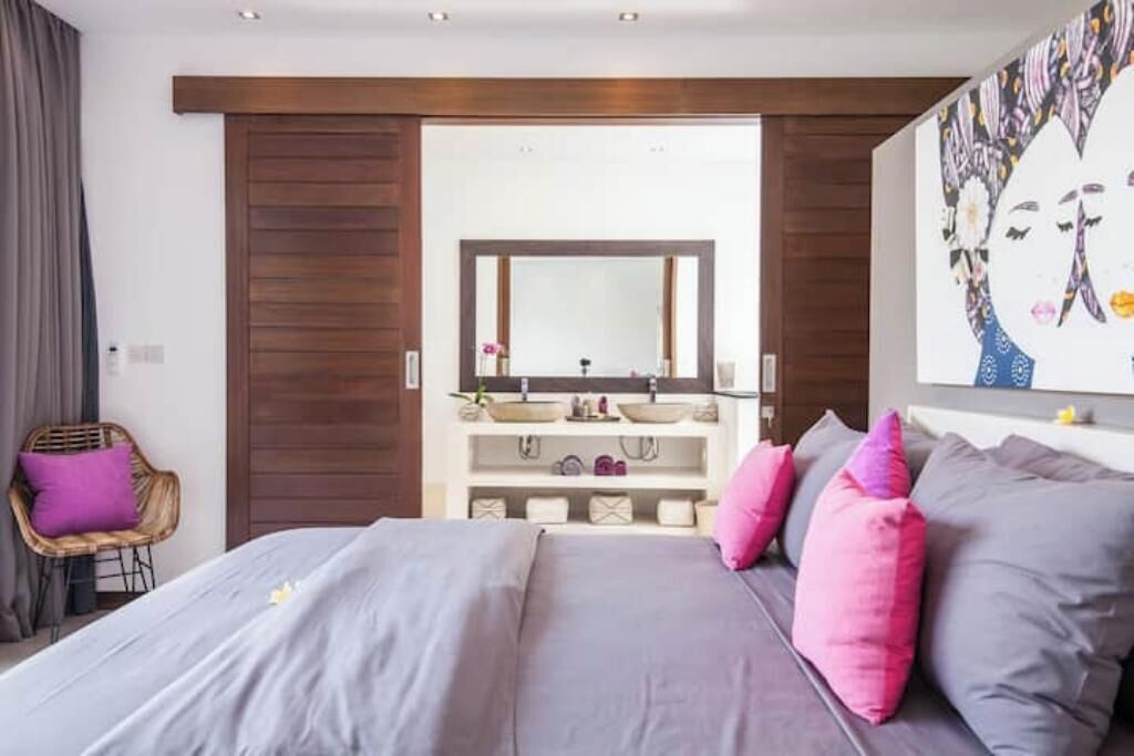 Une chambre à coucher avec un lit, une coiffeuse avec un miroir et un grand tableau accroché au mur.