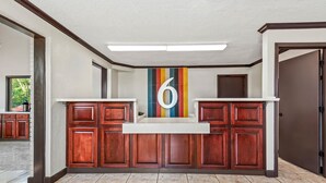 A reception area with a large number '6' on the wall, wooden cabinets, and a tiled floor. - Motel 6 Hammond, LA – I 12 – I 55 (Hammond)