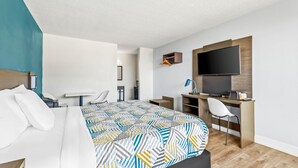 A hotel room with a bed, a desk, a chair, a TV, and a wall-mounted shelf. - Motel 6 Hammond, LA – I 12 – I 55 (Hammond)