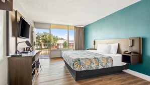 A hotel room with a large bed, a desk with a chair, a TV, and a balcony with a view of the outside. - Motel 6 Hammond, LA – I 12 – I 55 (Hammond)