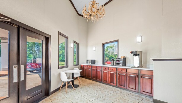 A modern kitchen with a built-in microwave, coffee machine, and a large window offering a view of the outdoors. - Motel 6 Hammond, LA – I 12 – I 55 (Hammond)
