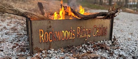 Una xemeneia metàl·lica amb la inscripció "Rockwoods Ridge Cabins", envoltada de grava i fulles seques.