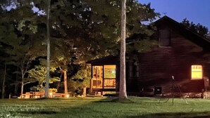 Eine rustikale Holzhütte, umgeben von Bäumen und einem grünen Rasen.
