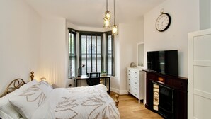 Ein Schlafzimmer mit einem Bett, einem Schreibtisch, einem Fernseher und einem Kamin.