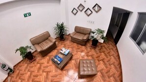 A spacious lobby with two leather sofas, a coffee table, and potted plants. - Hotel victoria Real (Tunja)